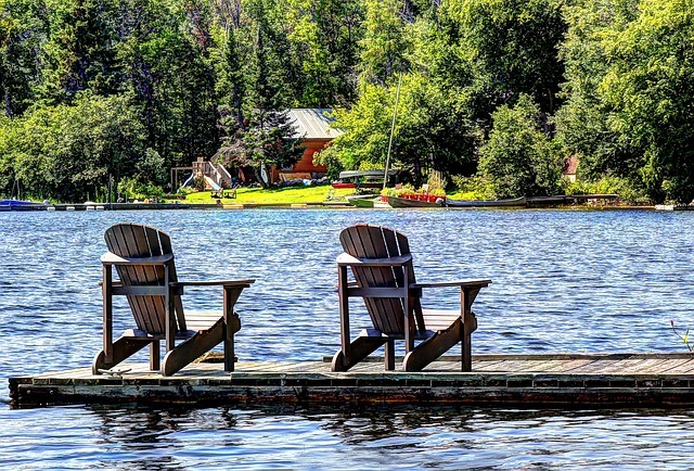 Two deck chairs out on the dock at a lakeside cabin.