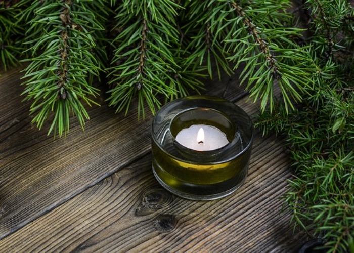 A photo of a tealight candle on a table surrounded by evergreen branches