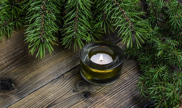 A photo of a tealight candle on a table surrounded by evergreen branches